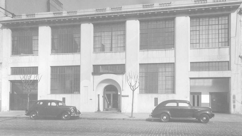 Fachada histórica de Laboratorios Andrómaco con autos antiguos